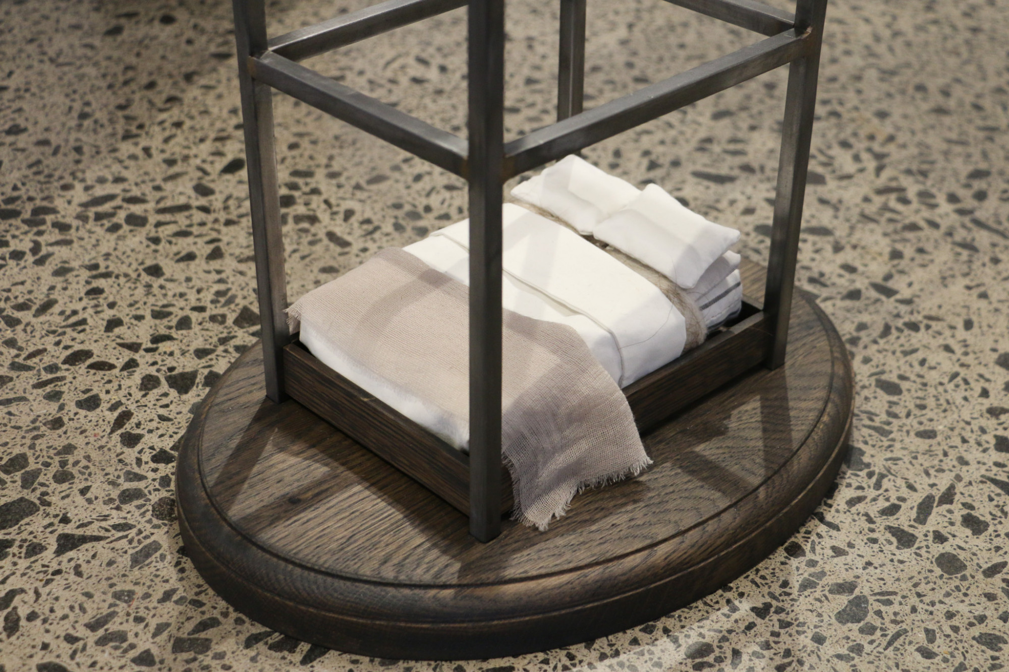 At the wooden base of a metal structure on the floor is a tiny bed.