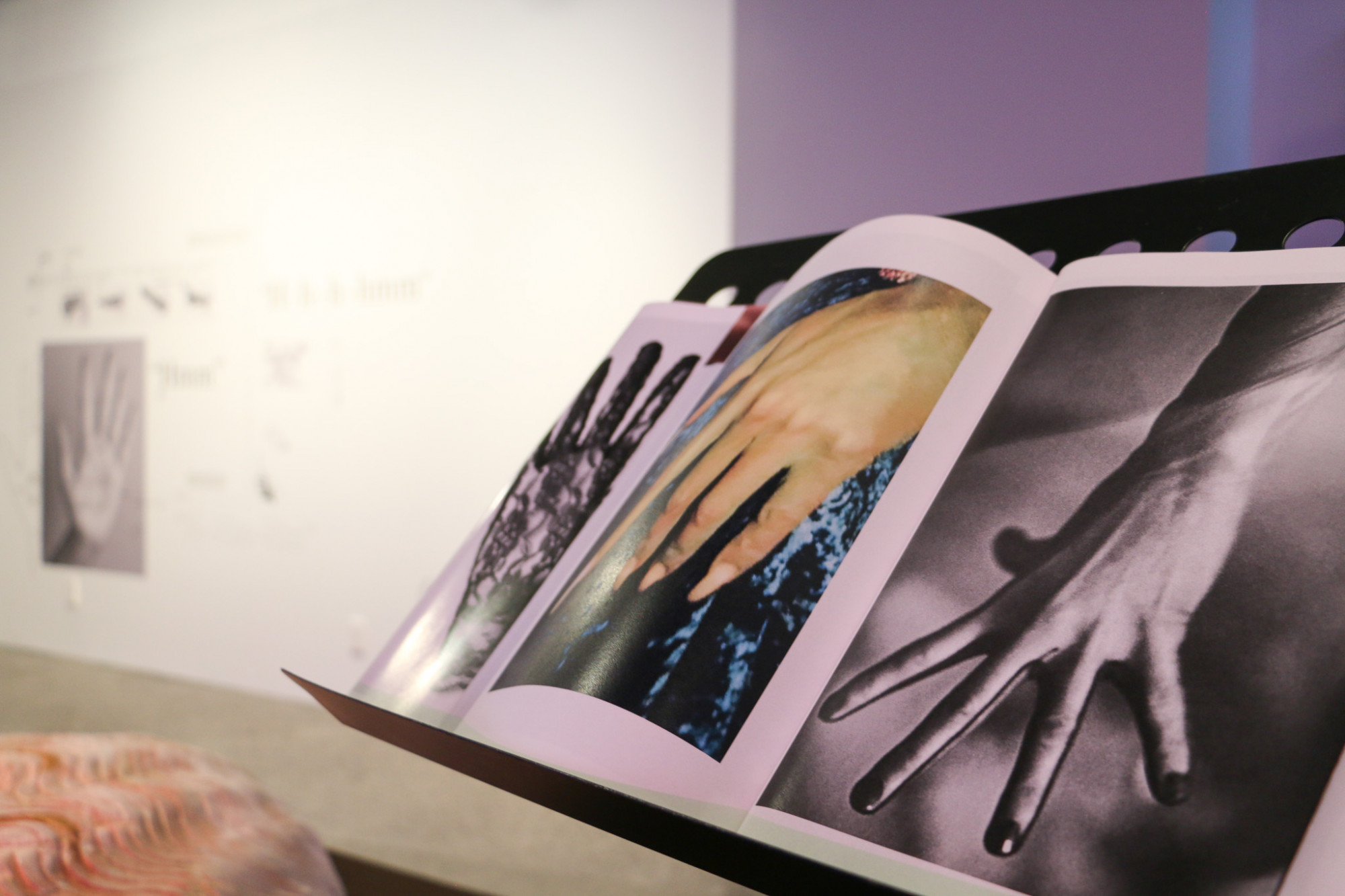 A music stand is holding a booklet, which is open with photographs of hands doing different gestures.