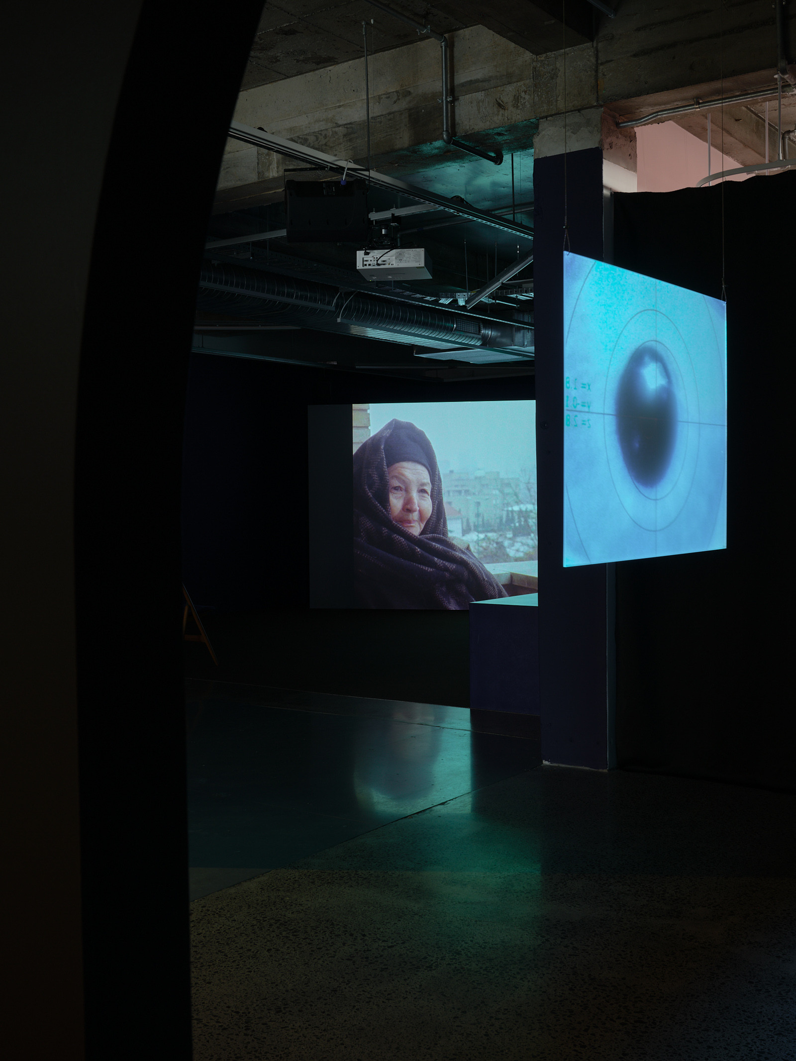 Two screens can been seen next to each other because of the view point, one with a pupil and the other of a woman looking at the camera.