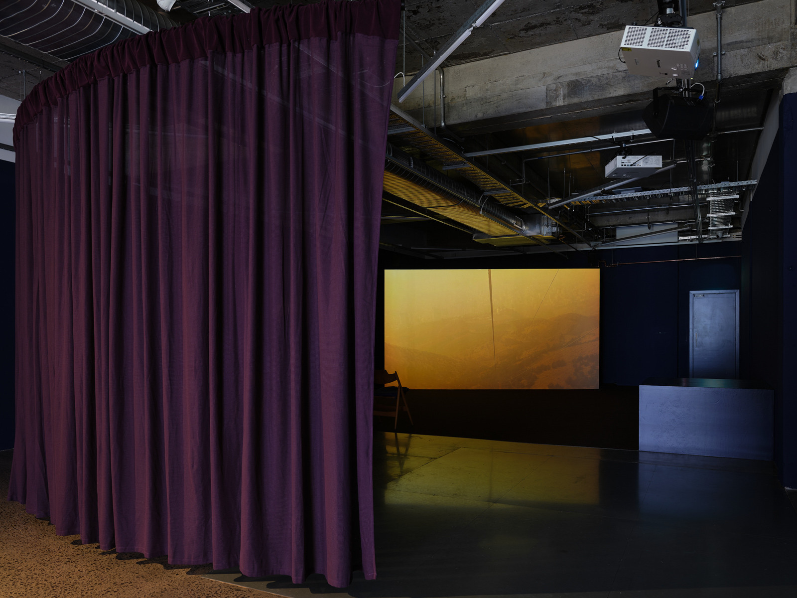 A purple curtain covers part of a screen with foggy orange light