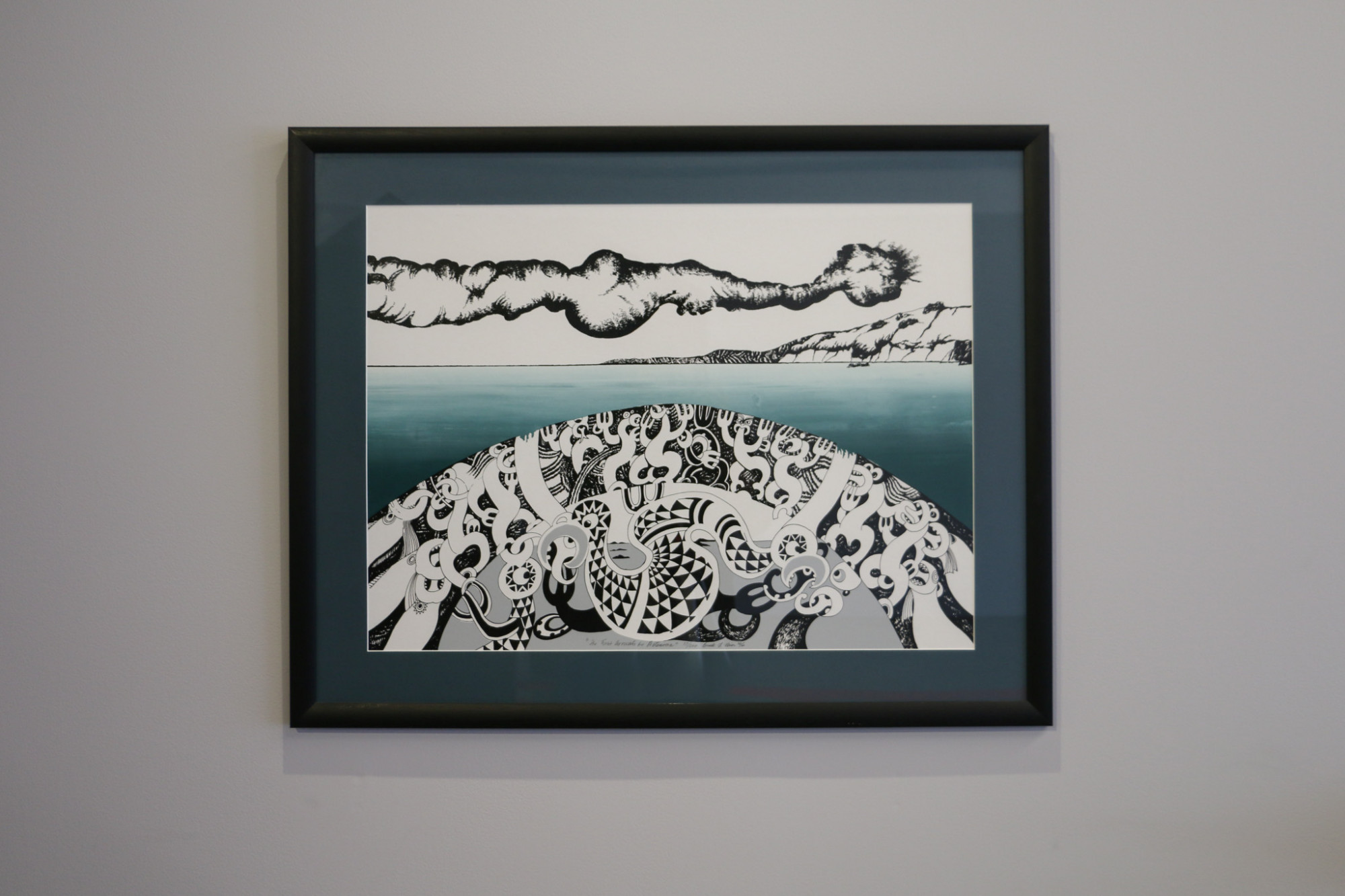 A framed print hung on the wall which depicts a landscape with a long cloud and sea and in the foreground a monochromatic crescent landscape filled with abstract figures.
