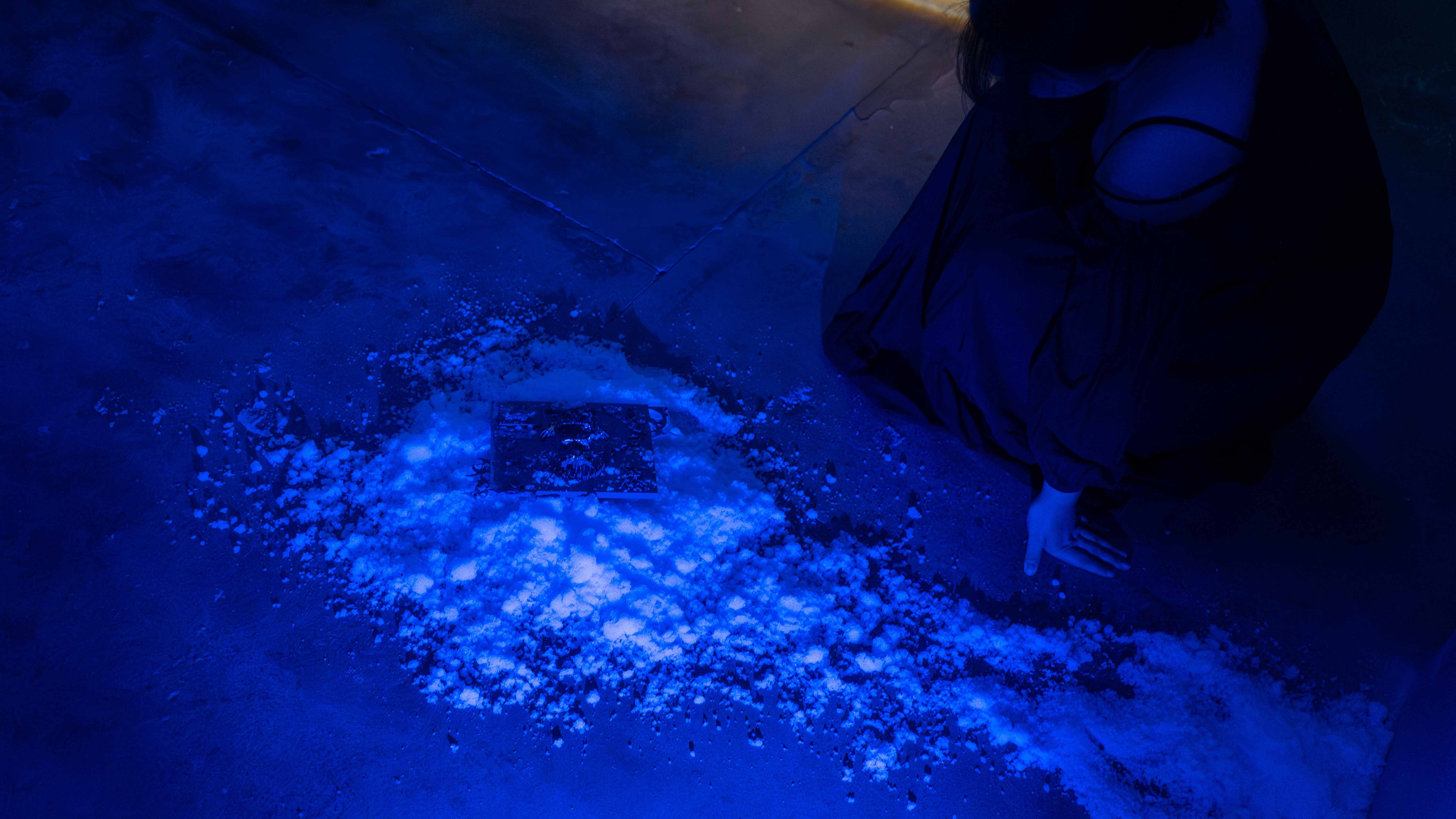 A hand-sized plastic tile with symbols and text sitting on a pile of white fake snow