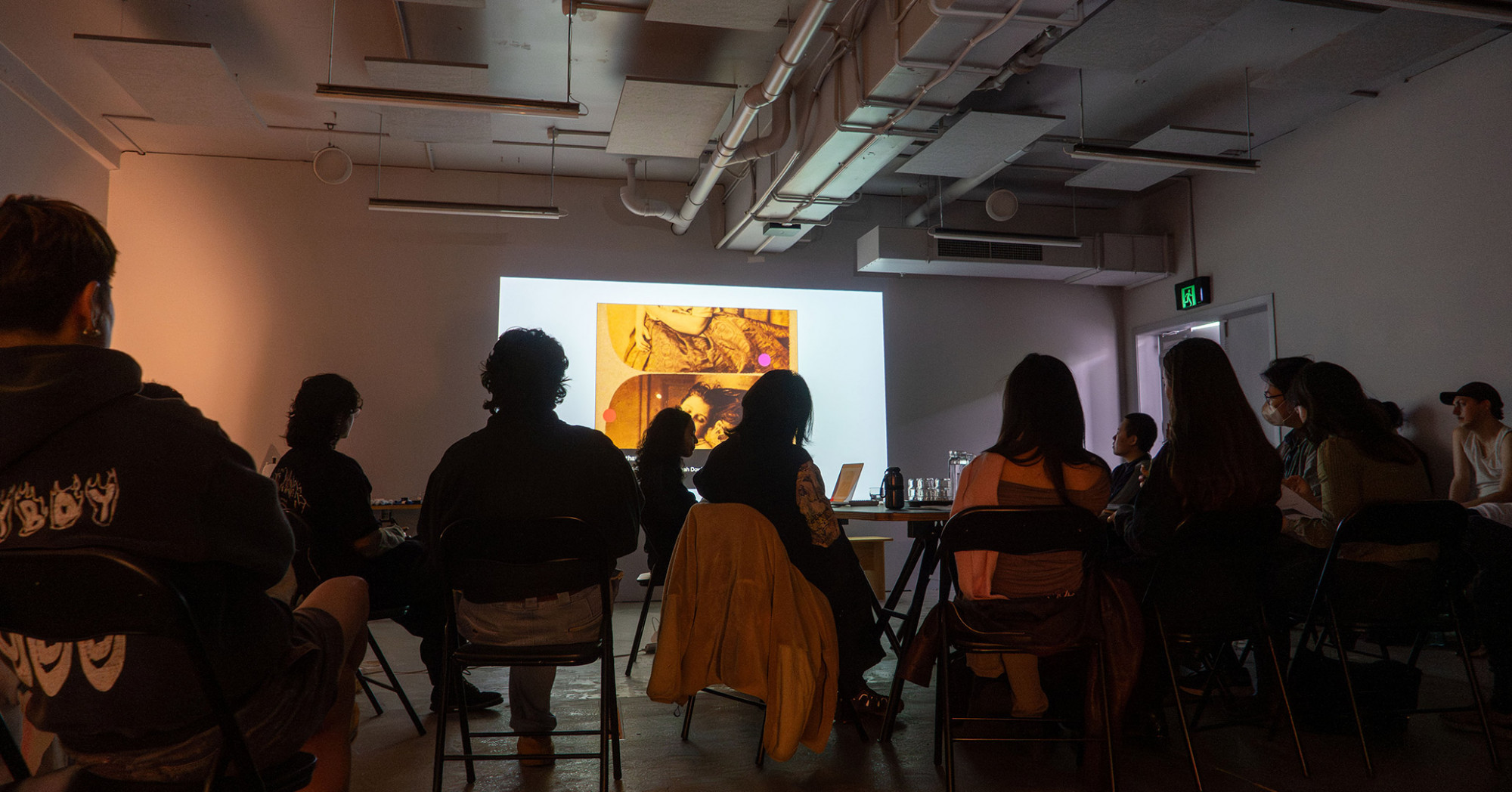 10 people sitting next to a big table in front of a powerpoint projection