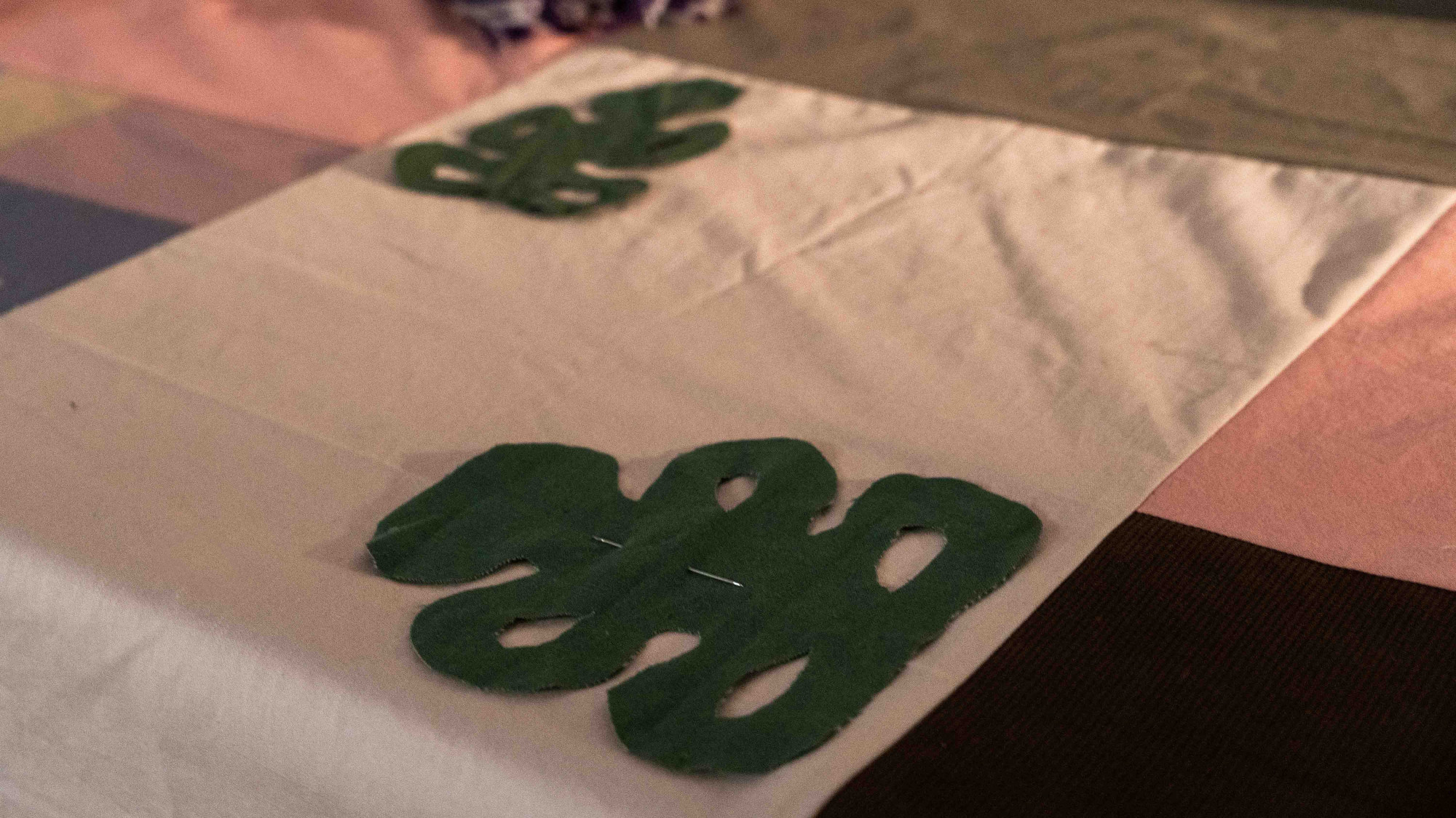 Two hei tiki pounamu cut from green fabric